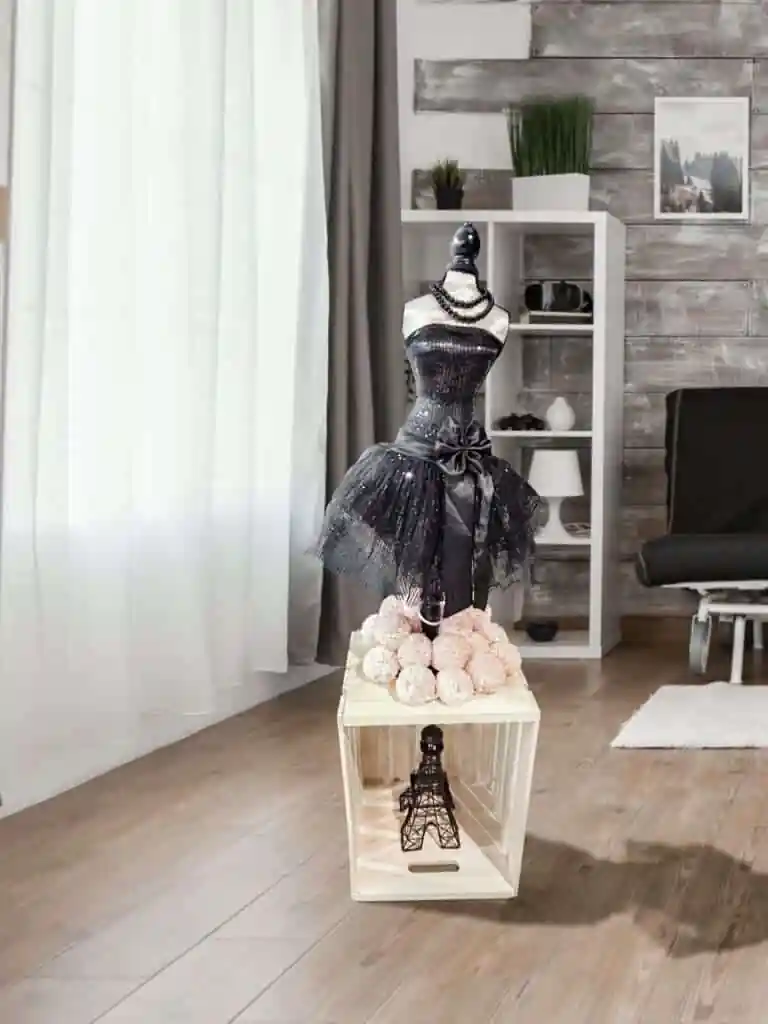 A black dress mannequin sitting on top of some pink flowers.