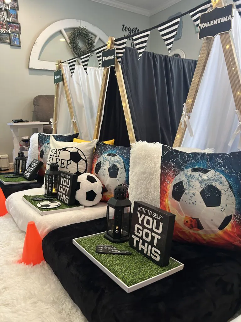 Soccer-themed kids teepee tents decorated with green grass mats and soccer ball pillows for a fun sleepover party.